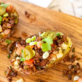 A wood board with loaded potato skins.