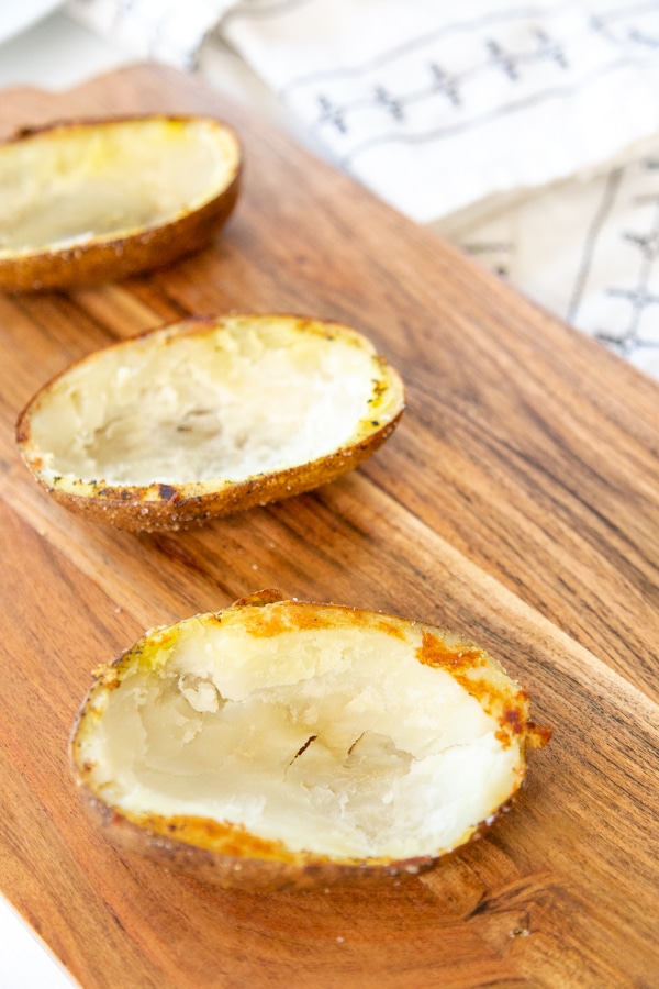 Baked potato halves with the center of the potato scooped out of them.