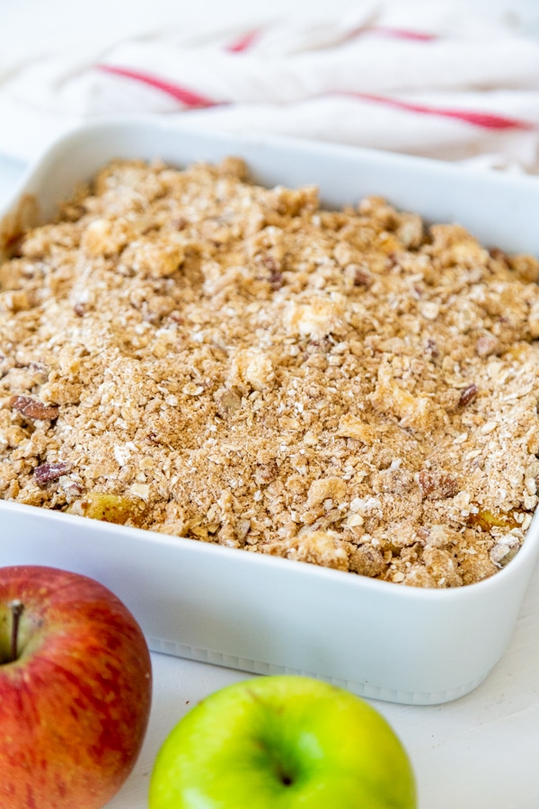 A white dish with unbaked apple crisp.