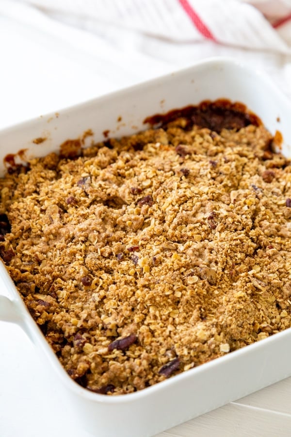 A square white pan with apple crisp in it.