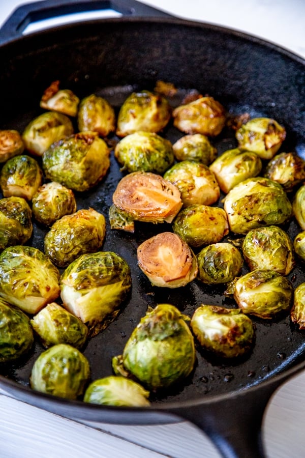 Roasted Brussels sprouts in a black iron skillet.