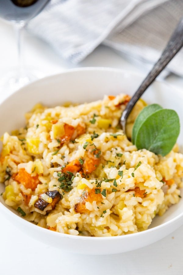 Squash risotto in a white bowl with a silver fork in the bowl.