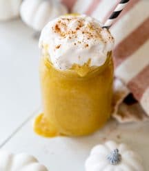 An overhead shot of a pumpkin smoothie with whipped cream and cinnamon and a black and white straw.