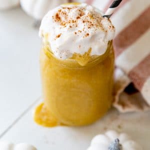 An overhead shot of a pumpkin smoothie with whipped cream and cinnamon and a black and white straw.
