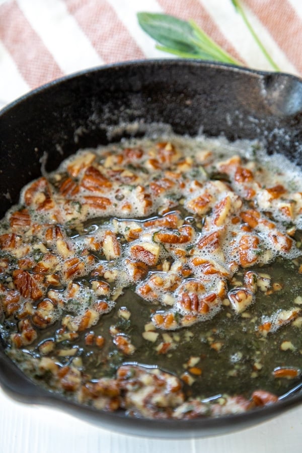 A pan of browned butter sauce with pecans.