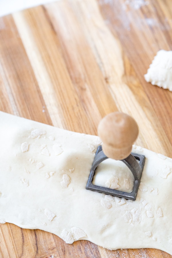 A hand pressing out homemade ravioli with a ravioli press.