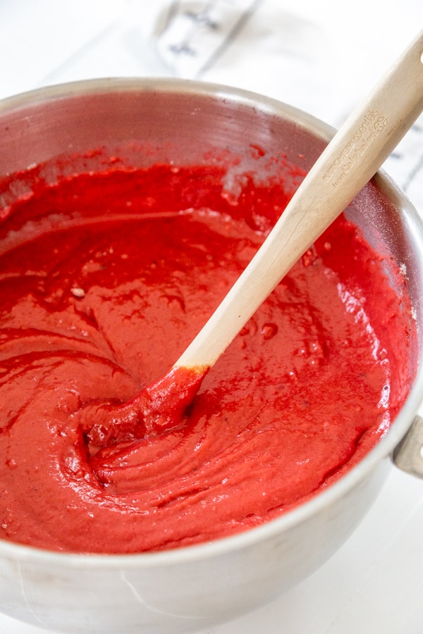 A bowl of red velvet cake batter with a spatula in the bowl