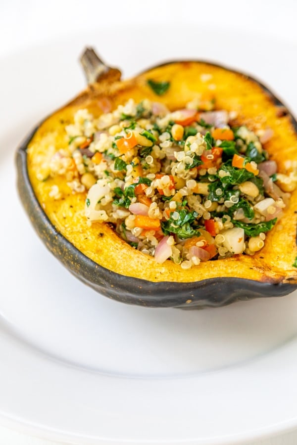 A close up picture of stuffed acorn squash on a white plate. 