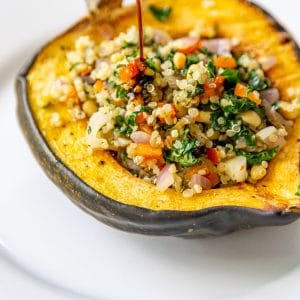 Balsamic glaze being poured over stuffed acorn squash.