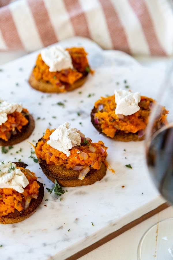 A marble board with sweet potato bruschetta topped with ricotta.