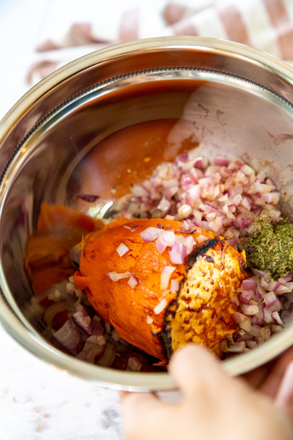 A bowl with roasted sweet potato, spices, and oil.