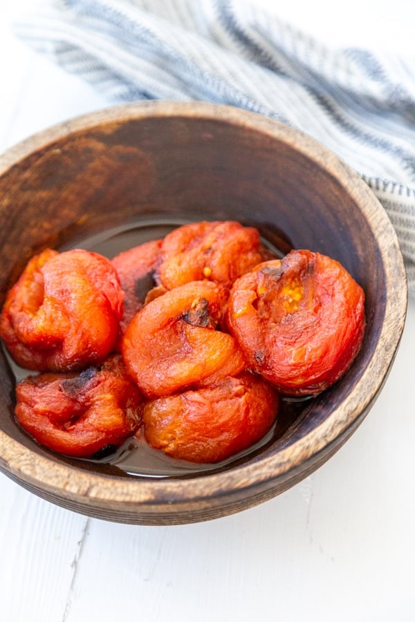 A wood bowl with roasted tomatoes.