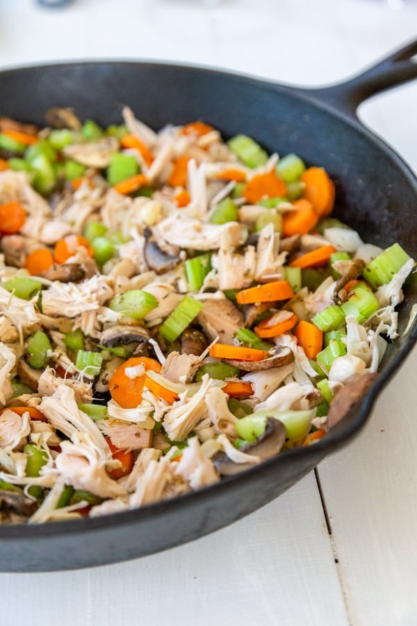 An iron skillet with carrots, celery, onion, and shredded jackfruit.