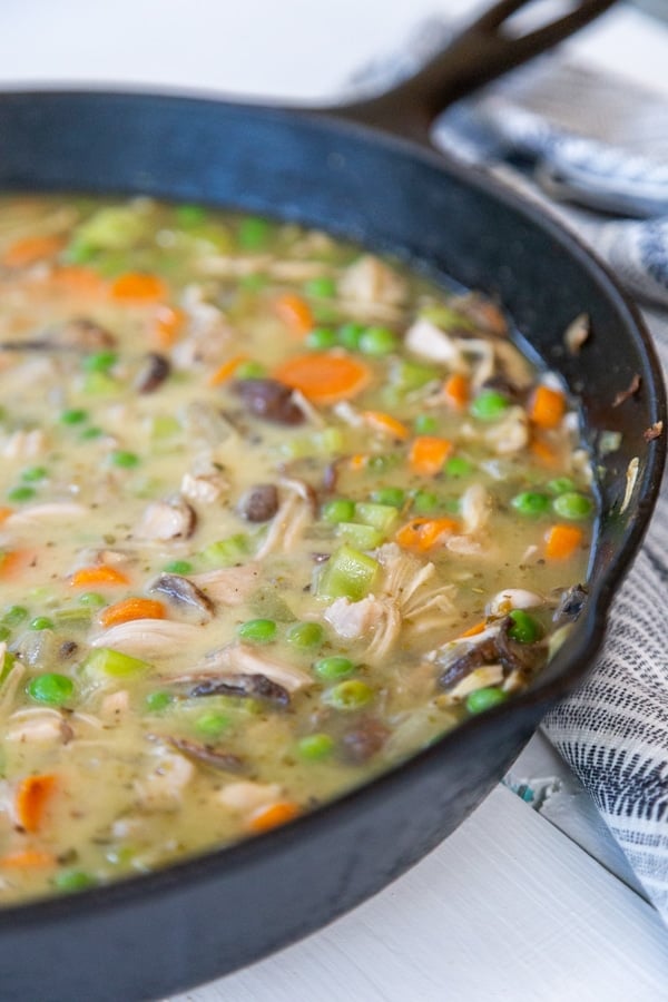 An iron skillet with vegetables and gravy. 