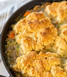 An iron skillet with chicken and biscuits.