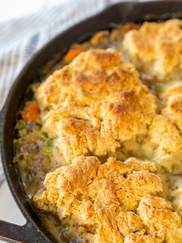 An iron skillet with chicken and biscuits.