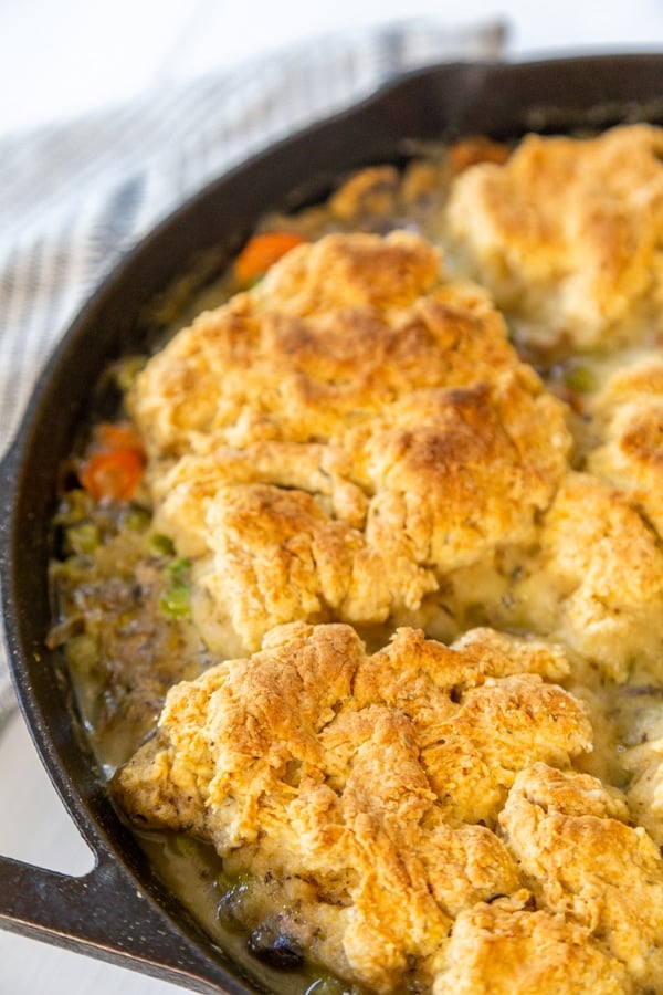 An iron skillet with chicken and biscuits. 