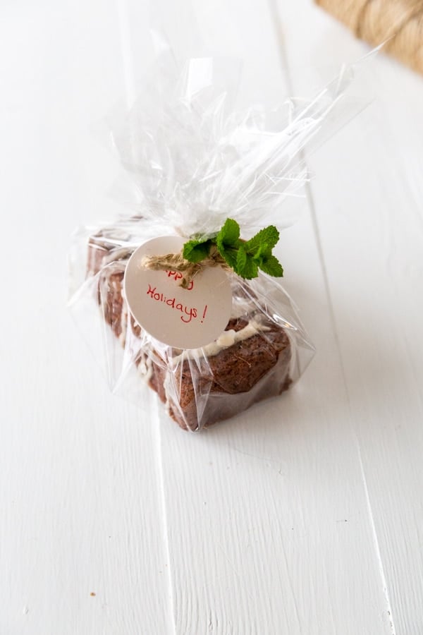 A chocolate loaf cake wrapped in cellophane with a ribbon and sprig of mint.
