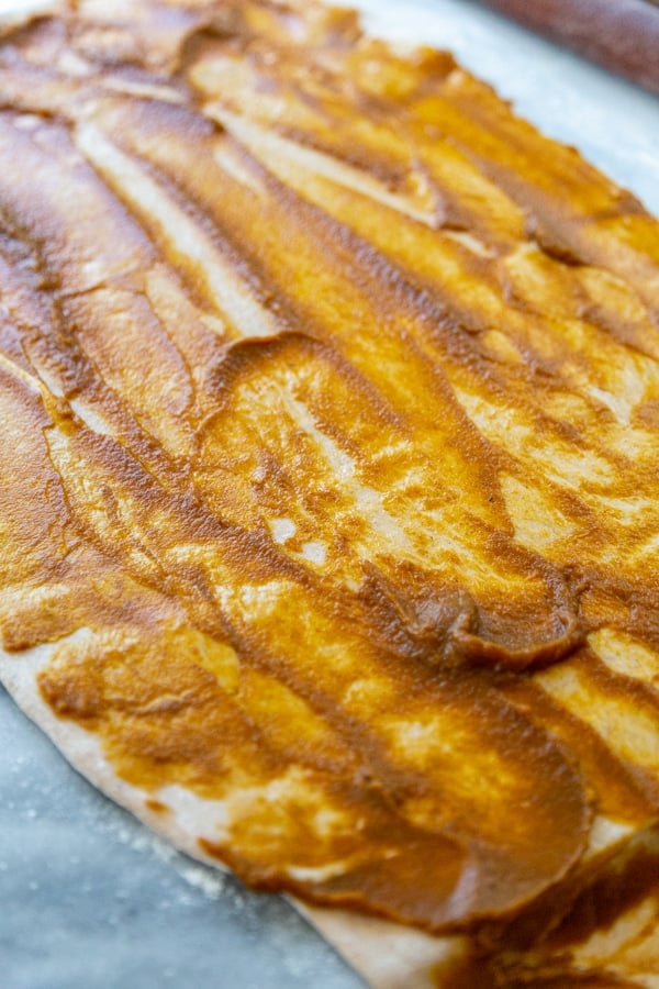 A rectangular piece of dough with pumpkin filling spread on top.