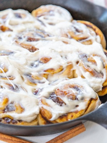 An iron skillet with frosted cinnamon rolls.