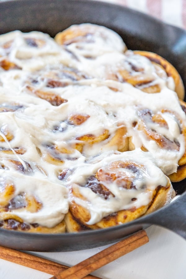 An iron skillet with frosted cinnamon rolls.