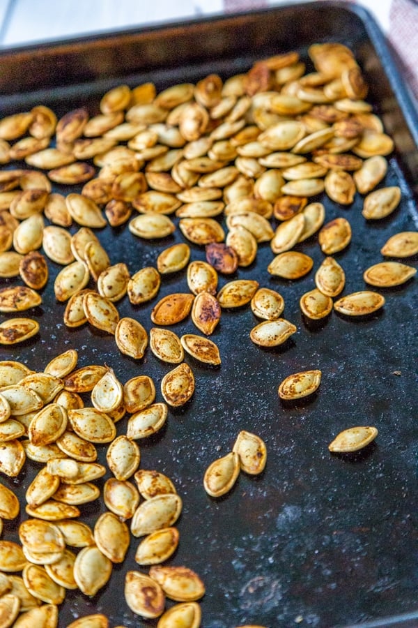 Roasted pumpkin seeds on a rimmed baking sheet.