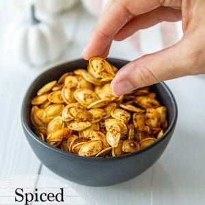 A PInterest pin for roasted pumpkin seeds with a picture of a hand taking the seeds out of a black bowl.