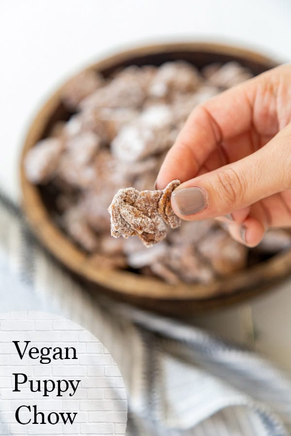 Vegan puppy chow being held in front of a bowl of vegan puppy chow in