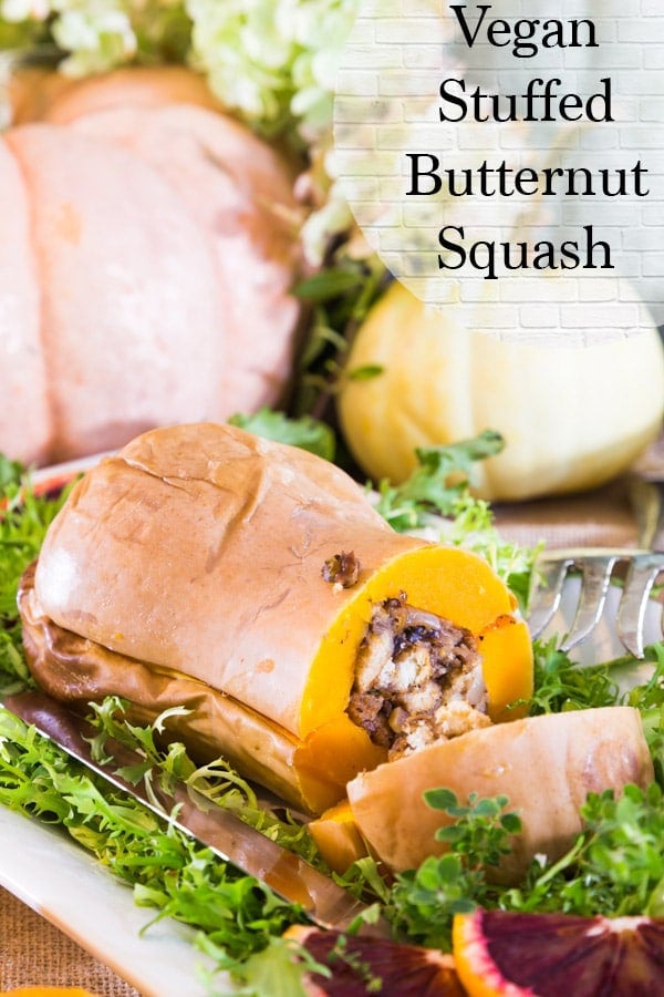 vegan stuffed butternut squash on a bed of greens and pumpkins in the background