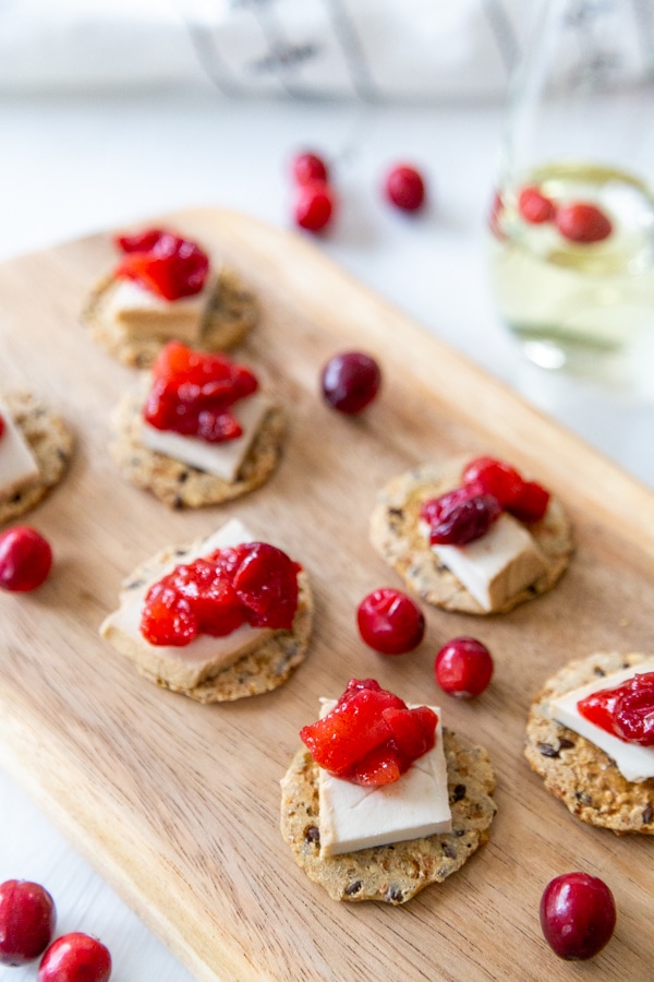 A board with cheese and crackers topped with cranberry apple compote.