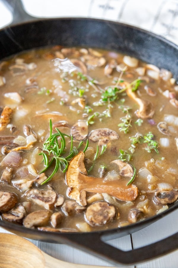 An iron skillet with mushrooms and gravy.