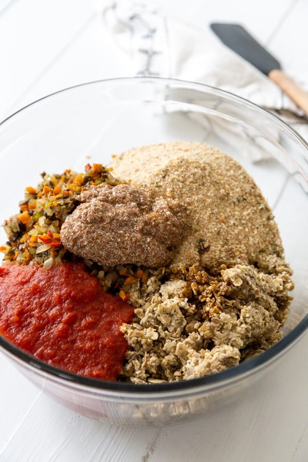 A clear glass bowl with the ingredients for a lentil loaf.