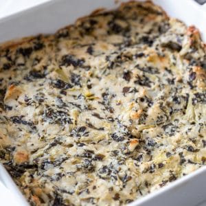 A square white dish with spinach artichoke dip.