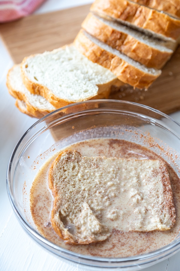 A slice of bread dipped into a bowl of milk and spices.