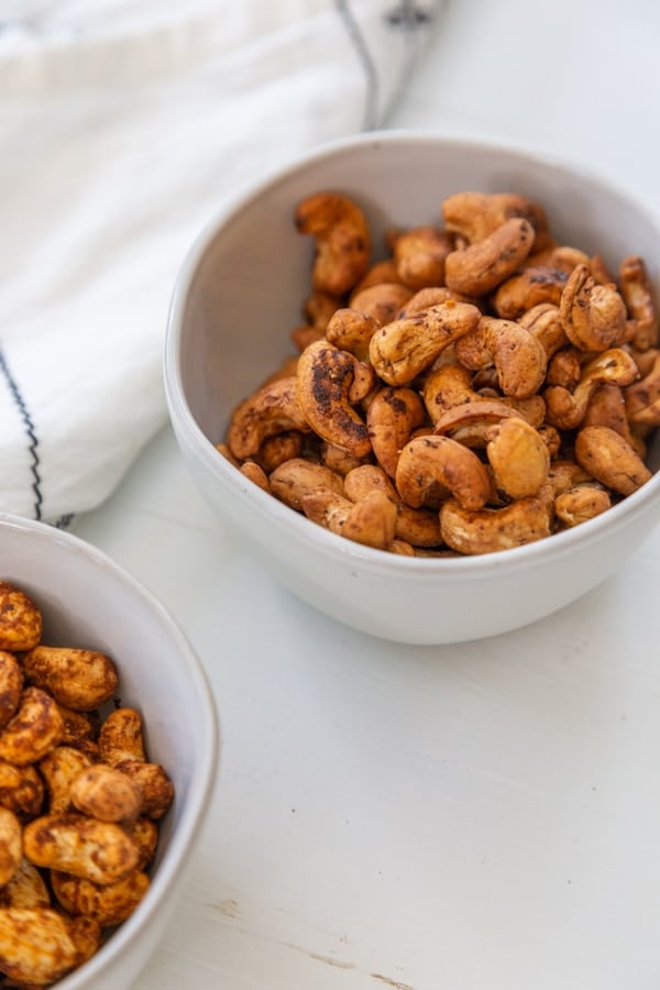 Two white bowls with roasted spiced cashews. 