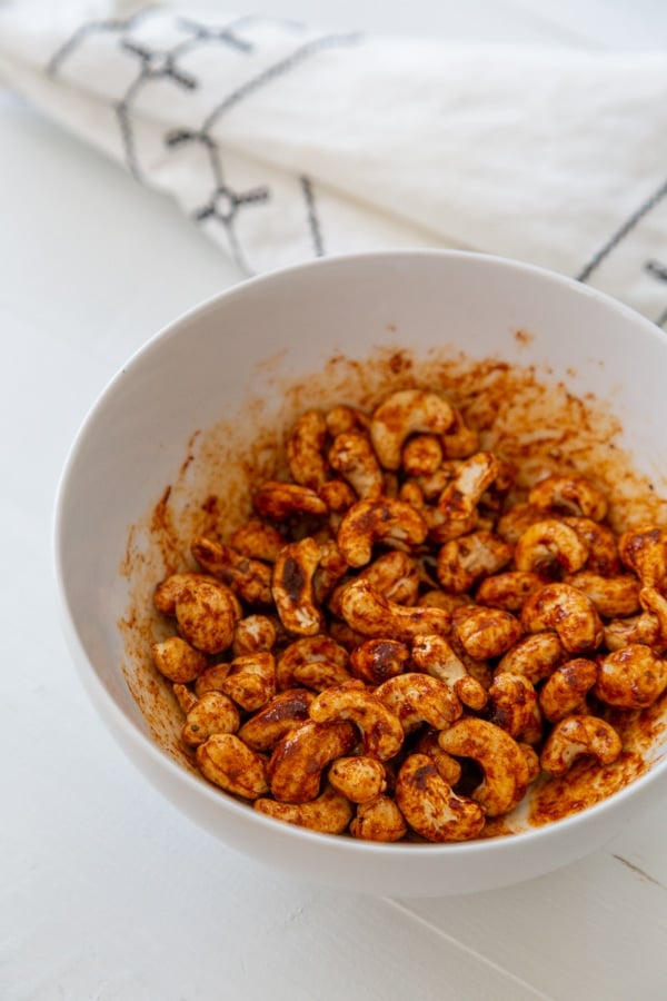 A white bowl with spiced cashews.