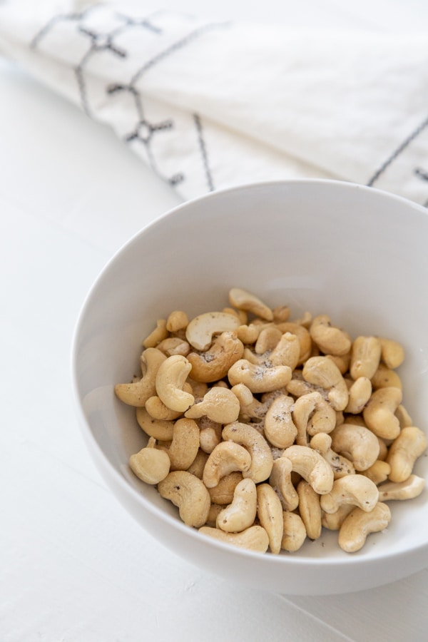 A white bowl with raw cashews and liquid smoke.