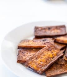 A stack of vegan tofu bacon on a white plate.