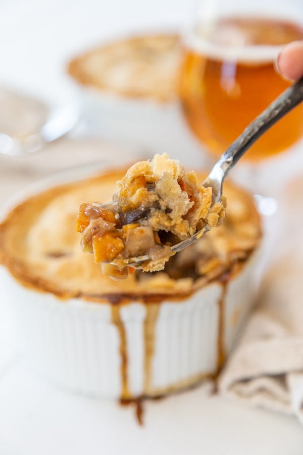 A fork digging into a pot pie in a white bowl.