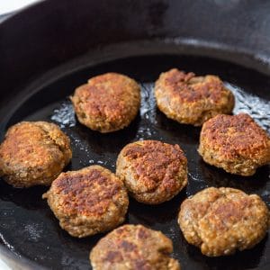An iron skillet with breakfast sausage patties.