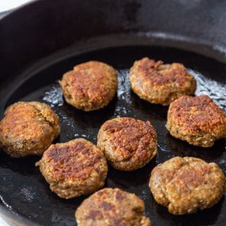 An iron skillet with breakfast sausage patties.