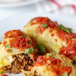 Stuffed cabbage rolls on a white plate and one is cut in half.