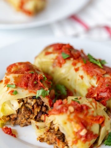 Stuffed cabbage rolls on a white plate and one is cut in half.