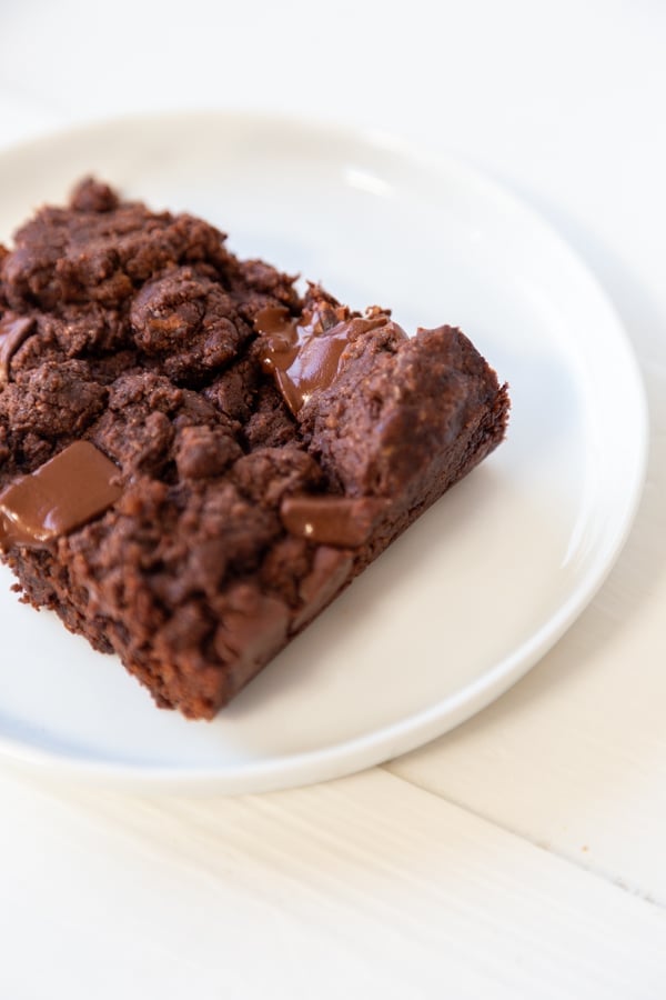 A brownie with chocolate chunks on a white plate. 