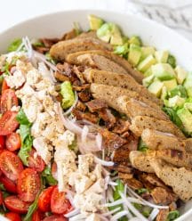 A white bowl with a Cobb salad in it.