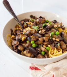 A white bowl with spaghetti and eggplant with a fork in the bowl.