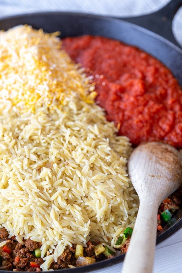 A cast iron skillet with orzo and tomatoes. 