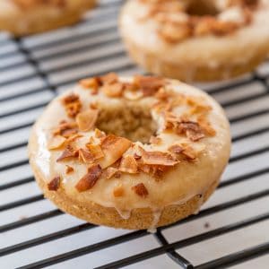 Doughnuts with coconut bacon chips on top cooling on a wire rack.