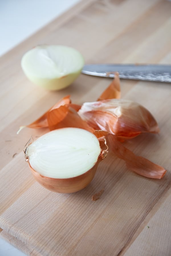 A cutting board with an onion cut in half. 