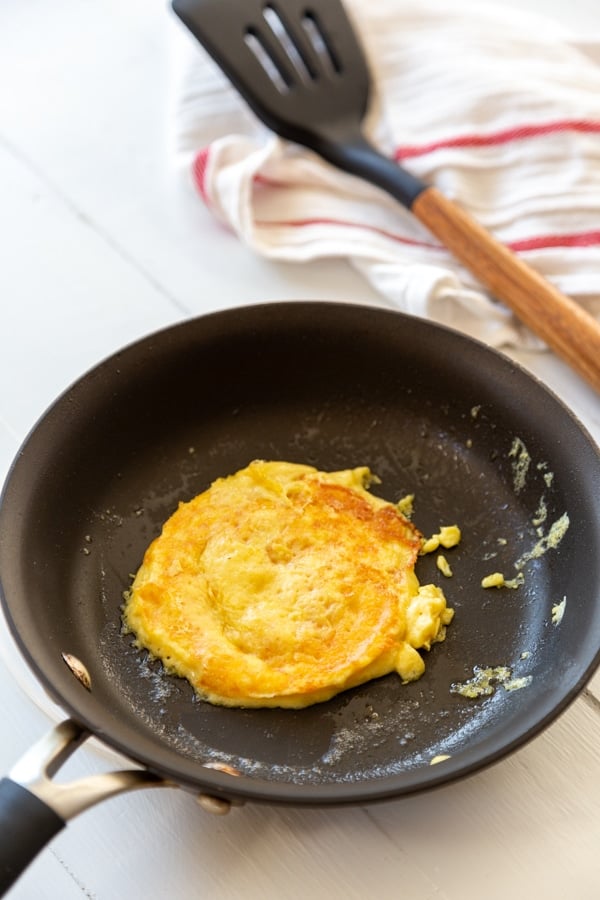 A skillet with a cooked egg and a spatula next to the pan on a towel.